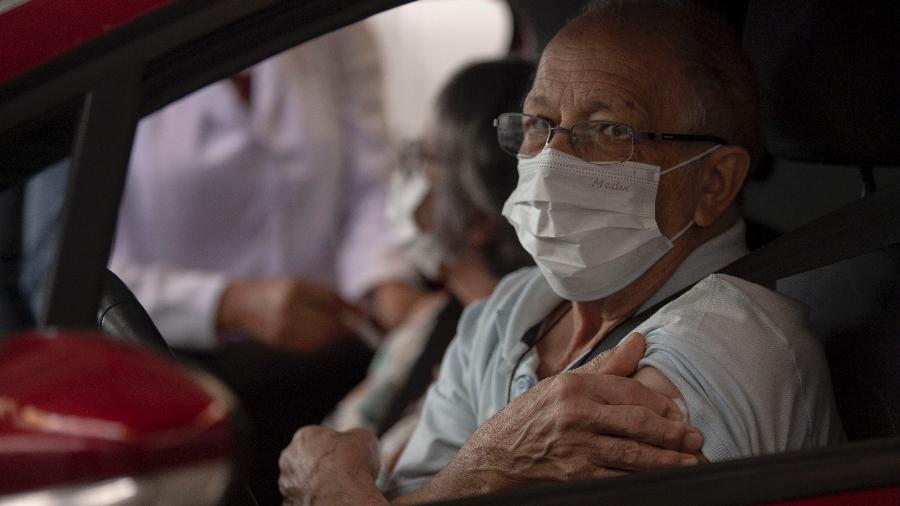 24.mar.2020 - De máscara, idoso recebe vacina contra a gripe no bairro da Tijuca, no Rio de Janeiro - Mauro Pimentel/AFP