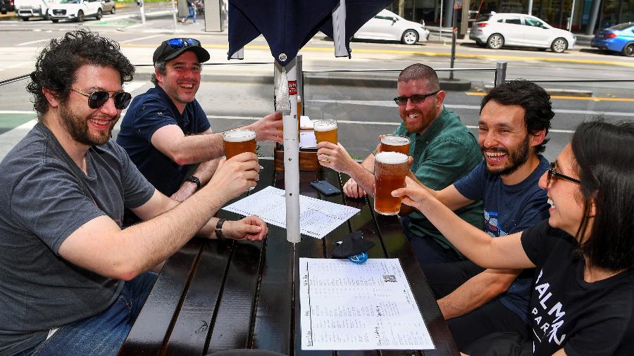 Clientes tomam uma cerveja em um pub no centro de Melbourne após reabertura - William West/AFP