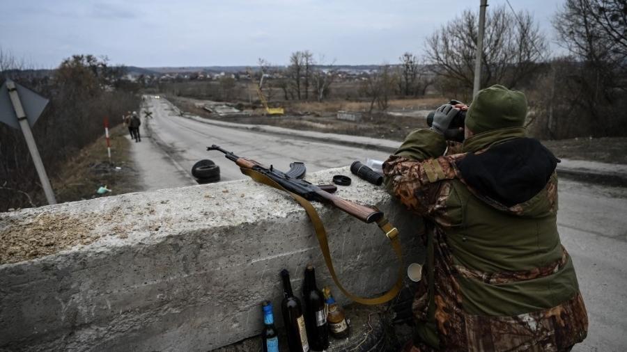 06.mar.2022 - Soldado da Ucrânia em posto de controle antes da última ponte na estrada que liga Stoyanka a Kiev - ARIS MESSINIS/AFP