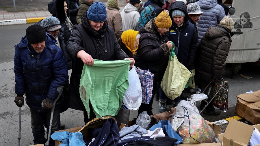 06.abr.2022 - Moradores de Buccha procuram roupas doadas em um ponto de doação de alimentos em Bucha, a noroeste de Kiev - RONALDO SCHEMIDT / AFP