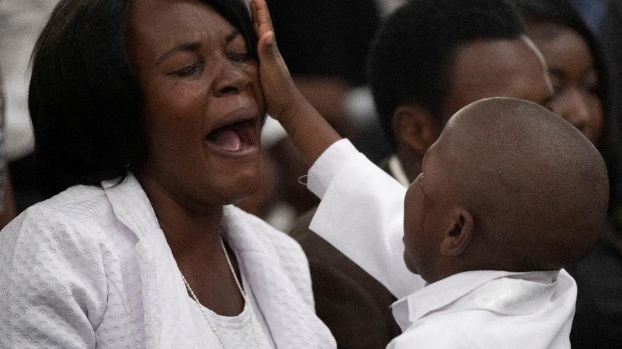 31.jan.23 - Criança enxuga as lágrimas de mulher em funeral em Porto Príncipe, no Haiti - Ricardo Arduengo/Reuters
