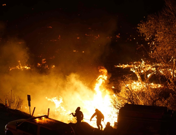 Bombeiros combatem o fogo próximo a casas de alto padrão, em Los Angeles, Califórnia - SANDY HUFFAKER/AFP