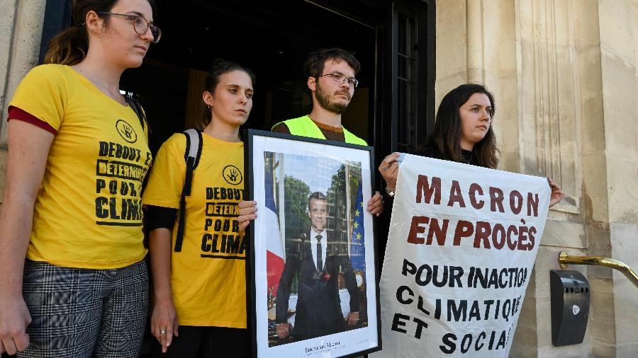 Ativistas do clima seguram uma foto do presidente francês Emmanuel Macron em frente à prefeitura de Saint-Ouen - Dominique Faget/AFP