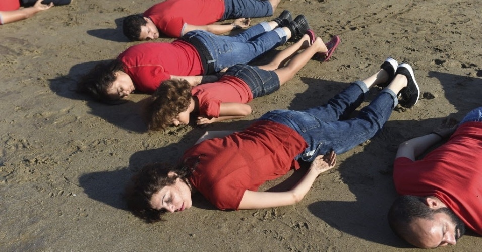 8.set.2015 - Manifestantes deitam em praia no Marrocos em posição semelhante à do menino sírio de três anos encontrado morto no dia 2 de setembro em uma praia da Turquia. A manifestação foi realizada no dia 7.