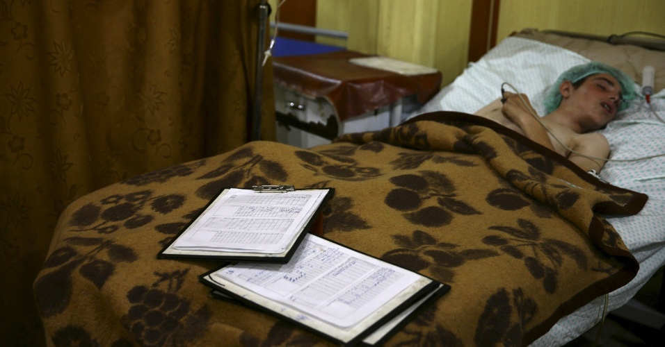 Jovem sírio repousa enquanto recebe tratamento em um dos abrigos transformados provisóriamente em hospitais onde médicos e voluntários trabalham em condições precárias na cidade síria de Douma