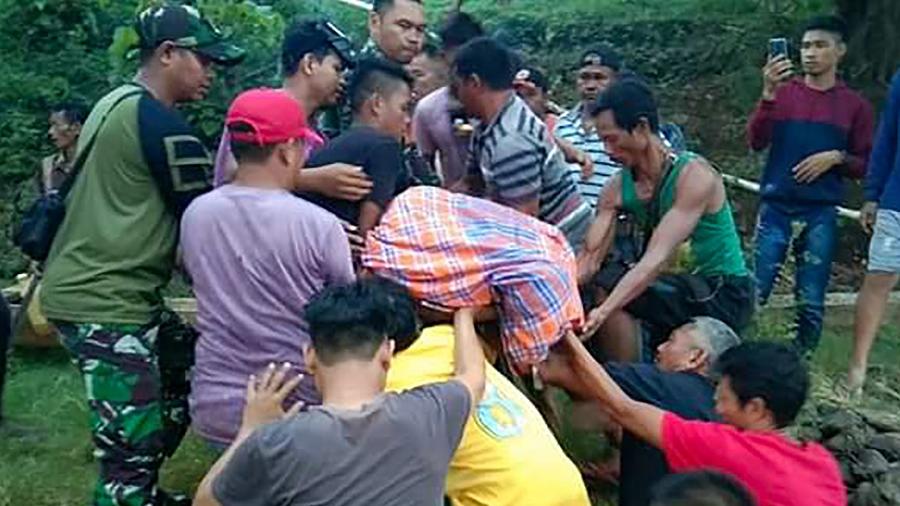 Grupo de pessoas remove o corpo de uma das vítimas dos ataques de crocodilo em Sulawesi, sudeste da Indonésia - Kendari search and rescue agency/AFP