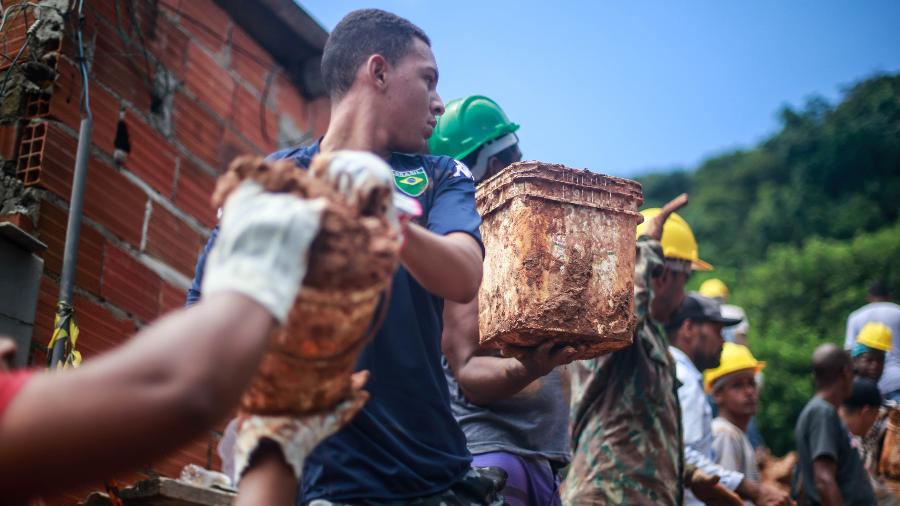 03.mar.2020 - Voluntários ajudam agentes do Corpo de Bombeiros no Morro do Macaco Molhado, em Guarujá, litoral de São Paulo - Werther Santana/Estadão Conteúdo