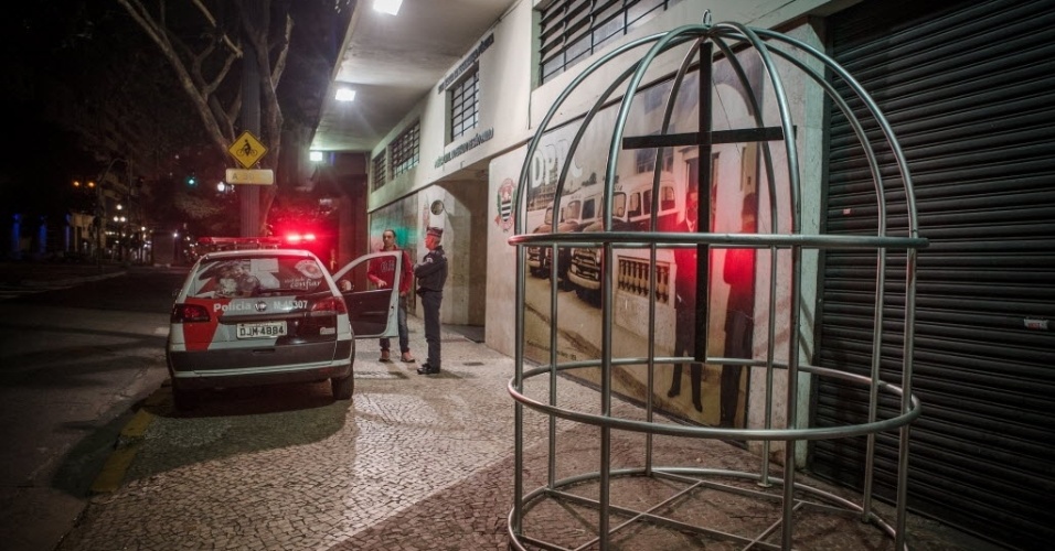15.ago.2015 - Uma cruz pendurada dentro de uma gaiola foi colocada em frente ao prédio do DPCC (Departamento de Polícia de Proteção à Cidadania), no centro de São Paulo, em um ato de protesto e solidariedade às famílias das vítimas de ataques em Osasco e Barueri. 