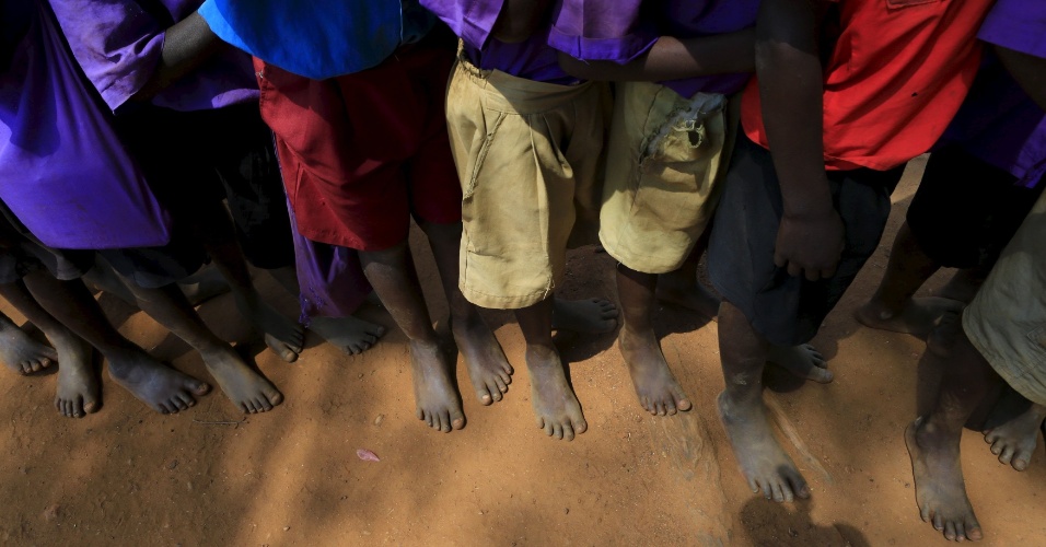 26.ago.2015 - Crianças em idade escolar fazem fila para remover "bicho-de-pé" dentro do projeto de extensão médica Sole Hope na vila Kalebera, distrito de Jinja, em Uganda