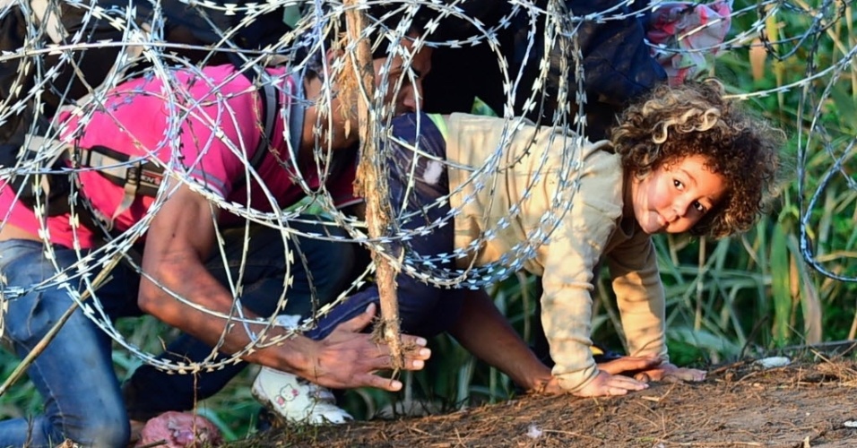 27.ago.2015 - Imigrantes rastejam por debaixo de uma cerca de arame farpado na fronteira entre a Hungria e a Sérvia. Segundo a polícia, mais de 141 mil imigrantes foram interceptados tentando entrar na Hungria em 2015