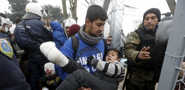 4.dez.2015 - Refugiado carrega um menino com uma perna quebrada pela fronteira entre Grécia e Macedônia - Yannis Behrakis/Reuters