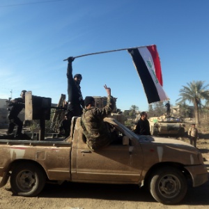 Forças contra-terroristas do Iraque agitam bandeira do país em Ramadi em automóvel que pertencia ao grupo extremista Estado Islâmico no início de dezembro - Ahmad Al-Rubaye/AFP