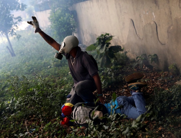 Ferido recebe ajuda de manifestante durante protesto contra Maduro - Carlos Garcia Rawlins/ Reuters