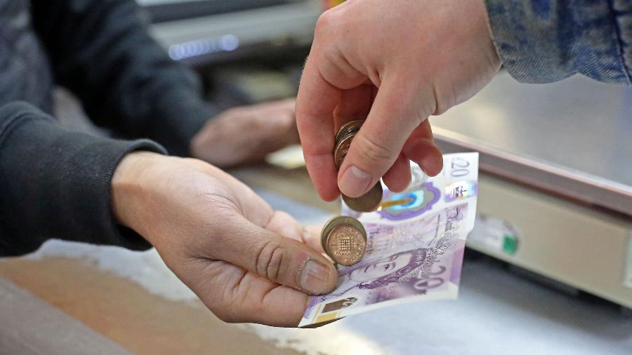 Cliente faz pagamento em libras esterlinas em uma loja de Londres, no Reino Unido - Susannah Ireland/AFP
