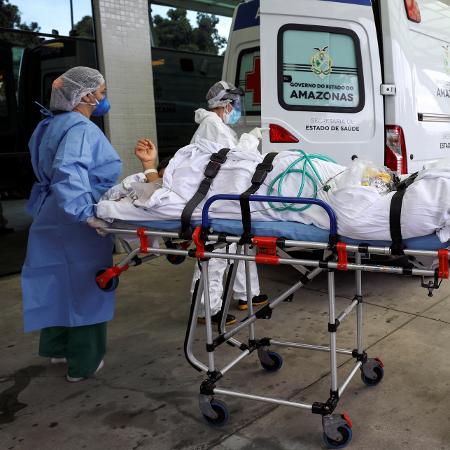 14.jan.2021 - Funcionários de hospital transportam paciente com covid-19 durante pico da pandemia em Manaus