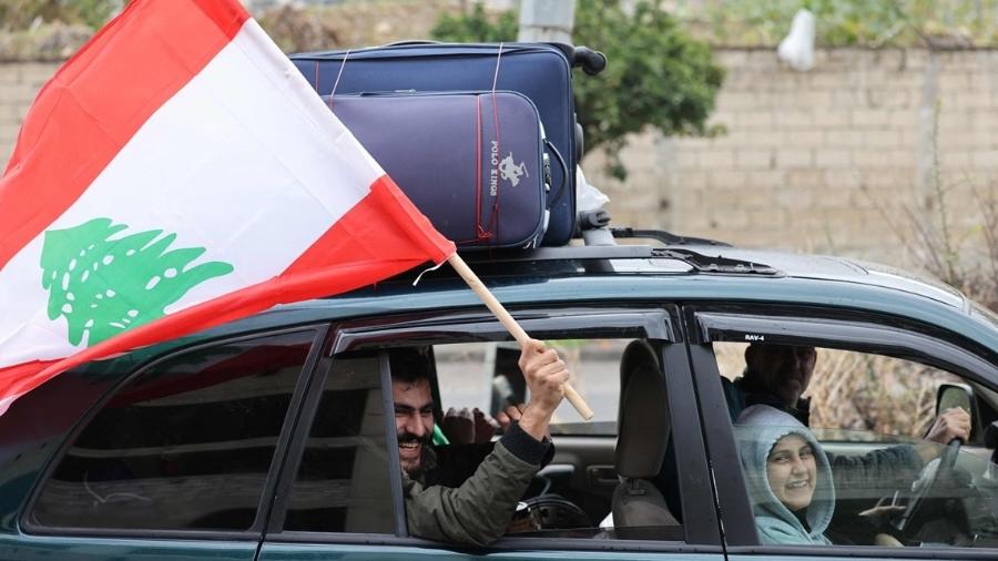 Homem mostra bandeira do Líbano ao voltar para casa, em Sidon, após cessar-fogo - anwar amro /27.nov.2024-AFP