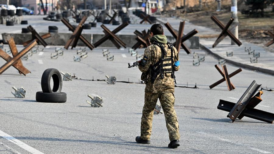 28.mar.2022 - Um soldado ucraniano passa por elementos de proteção antitanque enquanto monta guarda em um posto de controle nos arredores de Kiev, capital da Ucrânia. - Sergei Supinsky/AFP