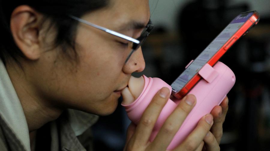 Jing Zhiuan usa um dispositivo para beijo remoto - Tingshu Wang/Reuters