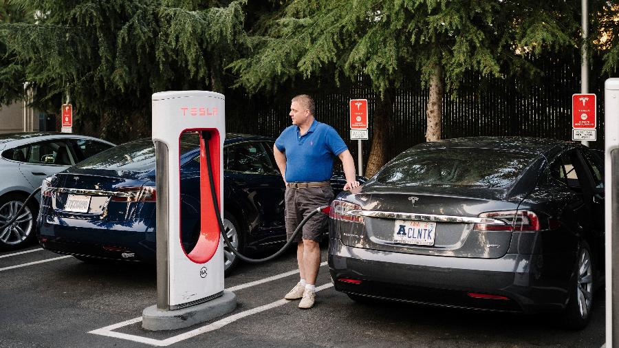Homem carrega seu carro Tesla em uma estação de recarga em Mountain View, Califórnia - JASON HENRY/NYT