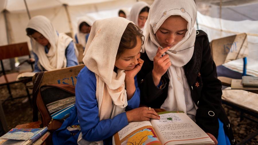 Estudantes compartilham livro didático durante as aulas em uma das tendas da Rustam School, em Yakawlang, no Afeganistão - Jim Huylebroek/The New York Times