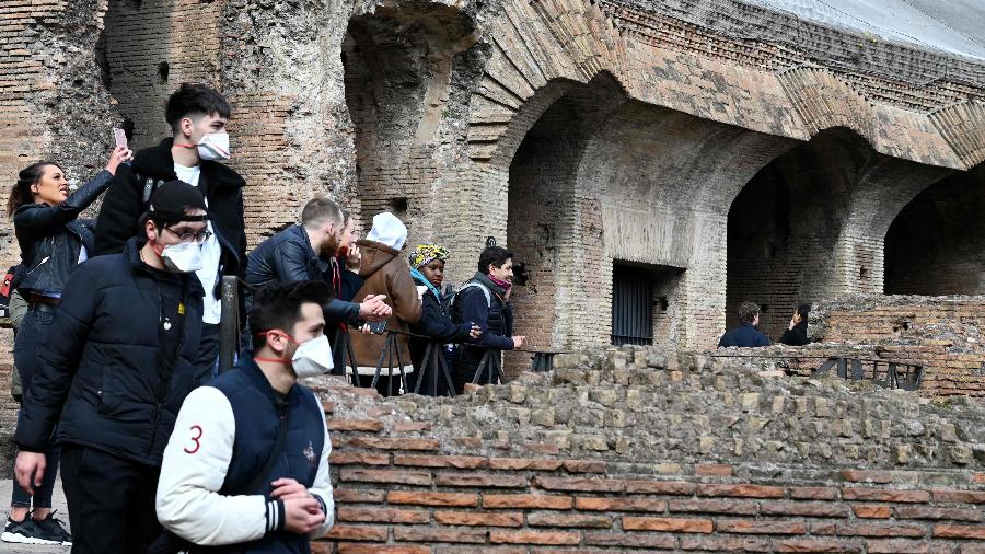 Turistas usam máscara durante visita ao Coliseu, o principal ponto turístico de Roma, na Itália - Tiziana Fabi/AFP