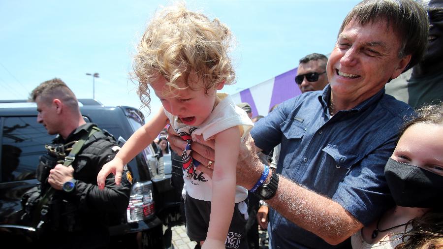 Jair Bolsonaro (sem partido) segura uma criança no bairro de Bento Ribeiro - WILTON JUNIOR/ESTADÃO CONTEÚDO