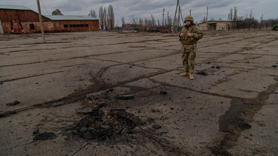 19.fev.2022 - Em Novoluganske, Ucrânia, soldado ucraniano observa local em que morteiro matou um capitão de seu batalhão na manhã de sábado - Yan Boechat/UOL