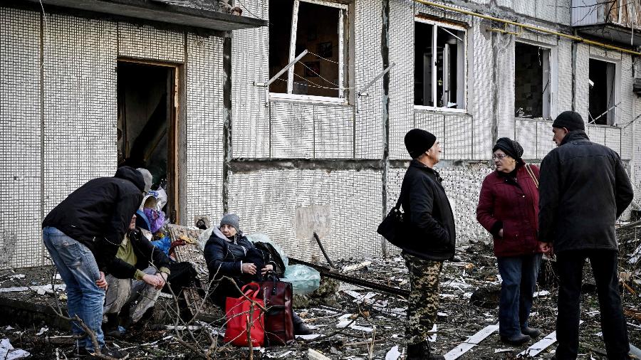 24.fev.2022 - Pessoas ficam do lado de fora de um prédio destruído após bombardeios na cidade de Chuguiv, no leste da Ucrânia - Aris Messinis/AFP
