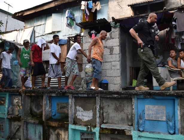 16.mar.2017 - Agente anti-drogas das Filipinas leva suspeitos durante busca em favela em Manila - Ted Aljibe/AFP