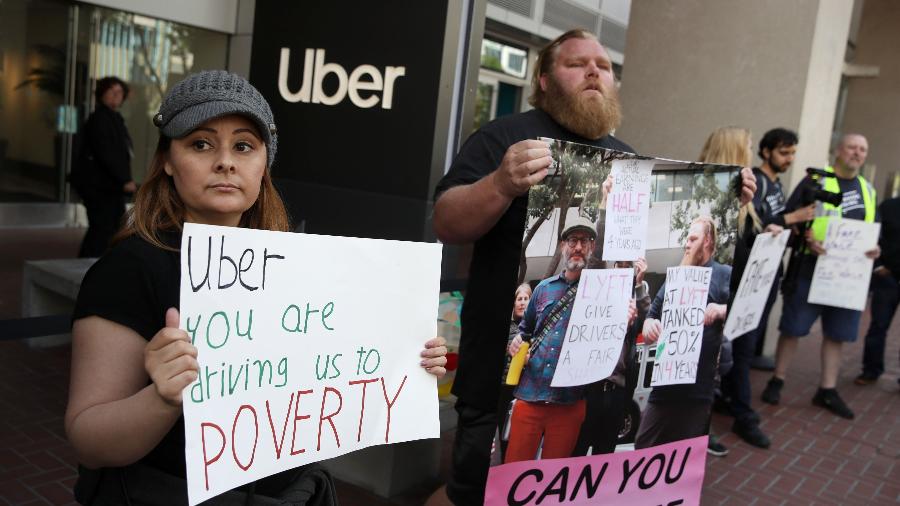 Motoristas de Uber e Lyft levantam cartazes em protesto na matriz do Uber, em San Francisco, Califórnia - Justin Sullivan/Getty Images/AFP