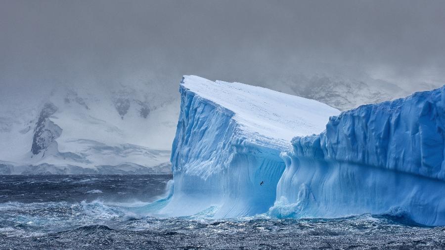 Enorme Iceberg flutuando no Oceano Antártico na Antártida com montanhas cobertas de neve ao fundo