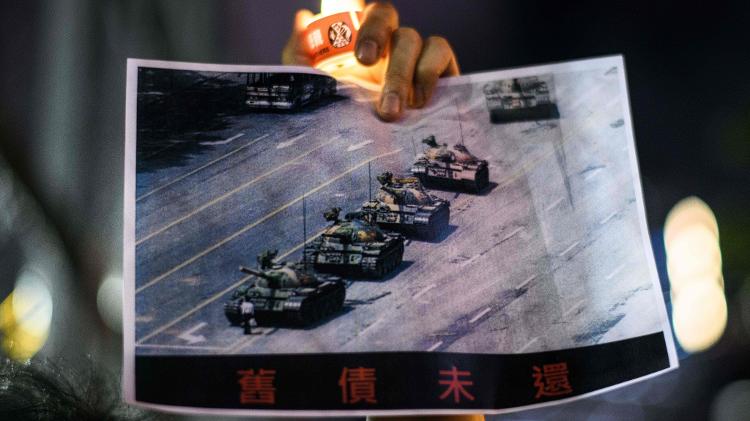 Um homem segura um pôster com a famosa foto de Jeff Widener, 'Tank Man', durante uma vigília à luz de velas no Victoria Park em Hong Kong em 4 de junho de 2020.