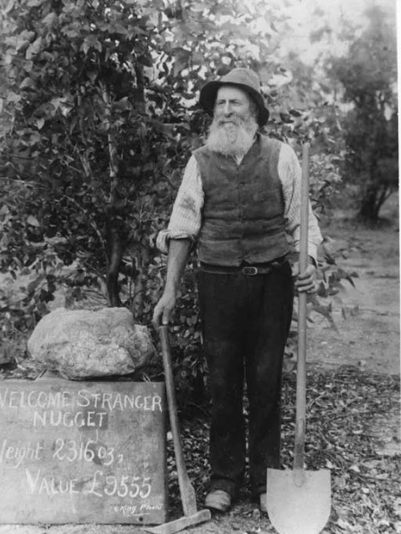 John Deason em fotografia de 1869, com uma réplica da pepita que ele encontrou com Oates