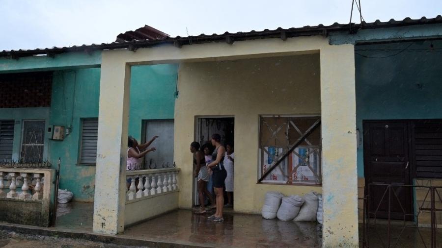 Uma mulher inspeciona sua casa durante a passagem do olho do furacão Rafael em Pueblo Candelaria, província de Artemisa, 65 km a oeste de Havana, em 6 de novembro de 2024