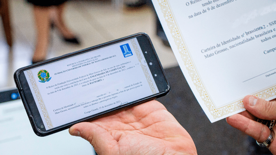 Diploma digital exibido no celular e versão impressa ao lado; desde julho de 2025, universidades brasileiras devem emitir apenas documentos digitais