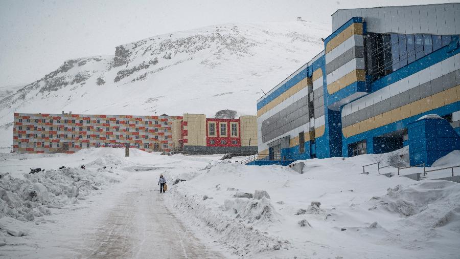 07.mai.22 - Vista geral mostra a cidade de Barentsburg na nevasca, enquanto uma mulher caminha na neve - JONATHAN NACKSTRAND/AFP