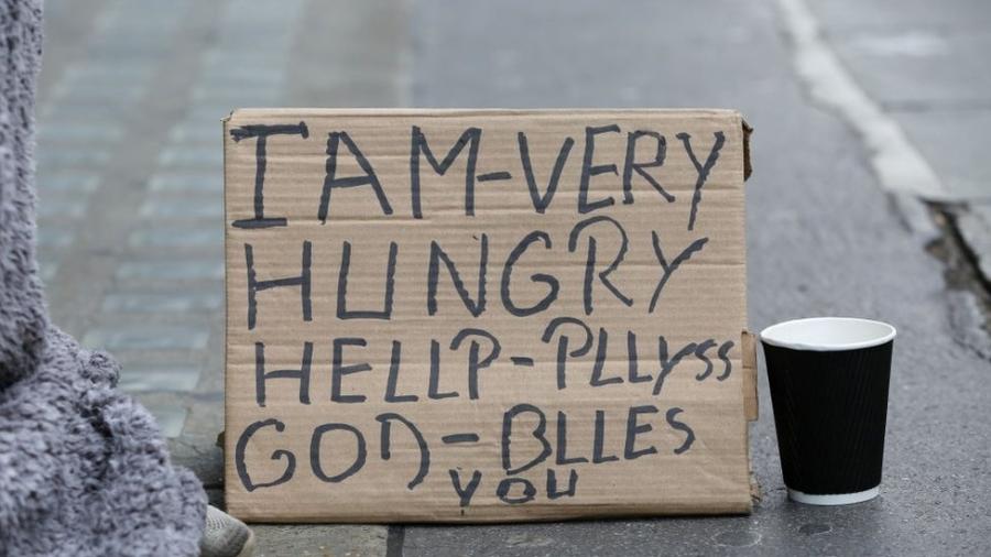 Cartaz de papelão diz, em inglês: "Estou com muita fome. Ajude, por favor. Deus te abençoe" - Getty Images