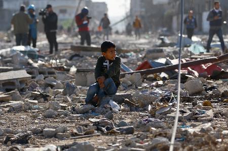 Criança palestina sentada entre os escombros de casas destruídas num ataque israelense em Khan Younis, no sul da Faixa de Gaza. - Ibraheem Abu Mustafa/Reuters