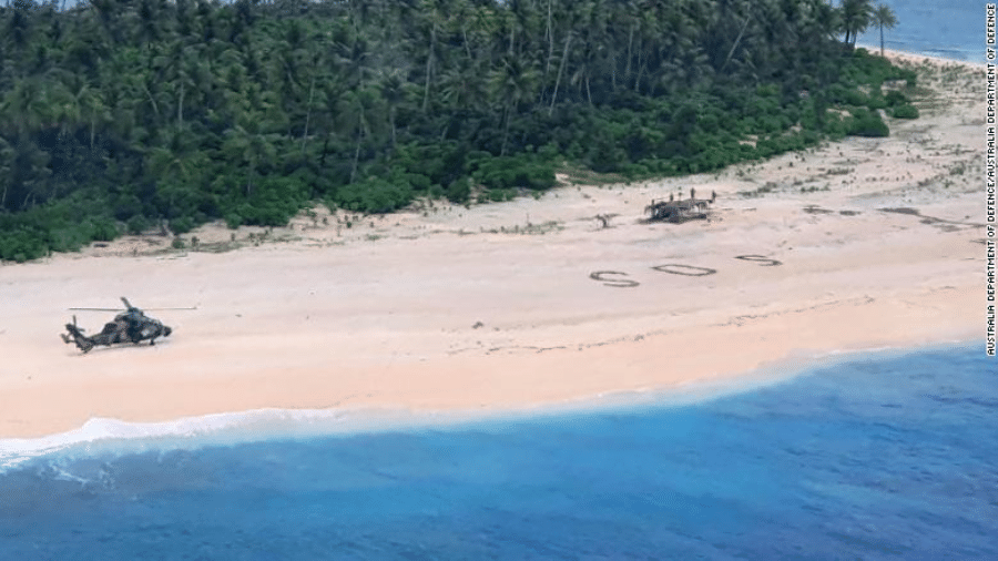 Helicóptero chega à ilha Pikelot, na Austrália, para resgatar três homens que estavam ilhados. Eles pediram socorro escrevendo SOS na areia - Reprodução/Departamento de Defesa da Australia