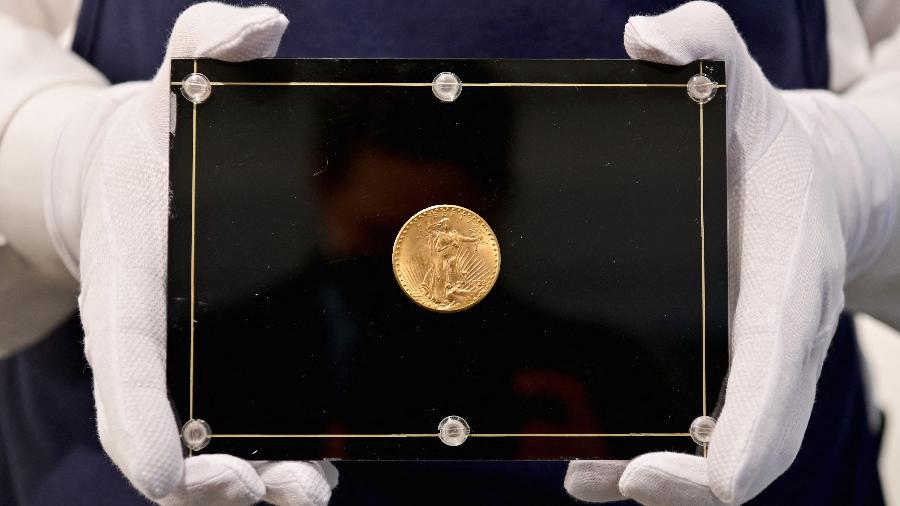 Um funcionário da Sotheby"s segura uma moeda Double Eagle de 1933 durante um leilão ao vivo; peça faz parte da última série de moedas de ouro - Angela Weiss / AFP