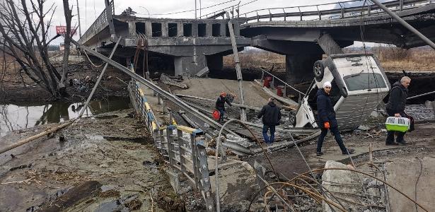 06.mar.2022 - Pedestres atravessam ponte destruída ao evacuar a cidade de Irpin, a noroeste de Kiev