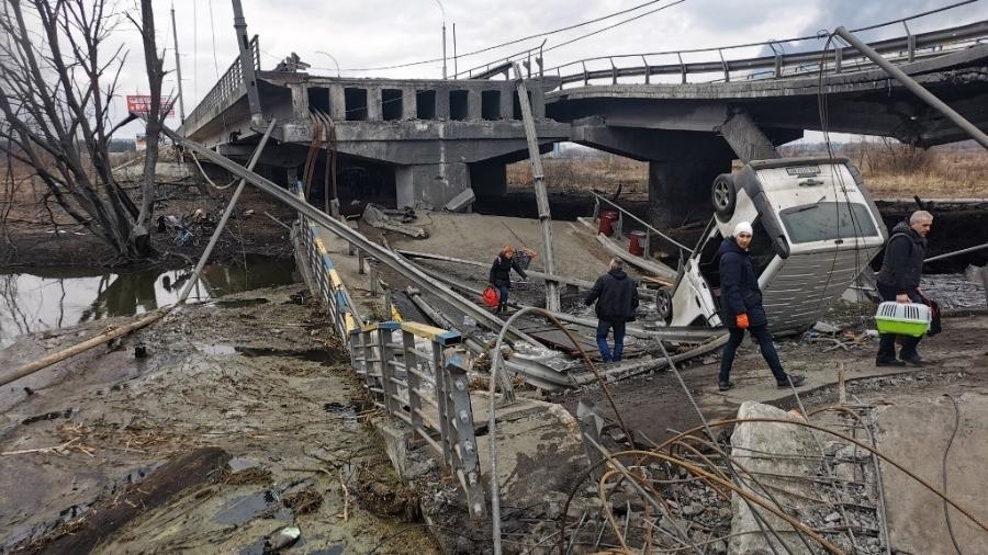 06.mar.2022 - Pedestres atravessam uma ponte destruída ao evacuar a cidade de Irpin, a noroeste da capital da Ucrânia, Kiev, em 6 de março de 2022, 11 dias após a Rússia lançar uma invasão militar no país. - DAPHNE ROUSSEAU/AFP