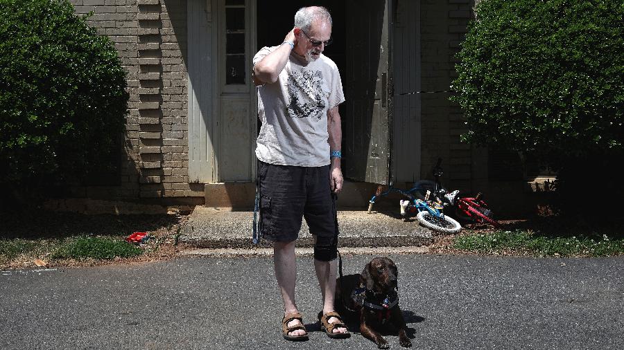 Steve Singer, que tem transtorno bipolares, com seu cão de serviço, Tiger, em frente a seu apartamento em Charlotte - Travis Dove/The New York Times