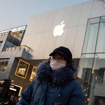 Coronavírus: Mulher usa máscara de proteção em frente a uma loja da Apple em Beijing, na China - Nicolas Asfouri/AFP