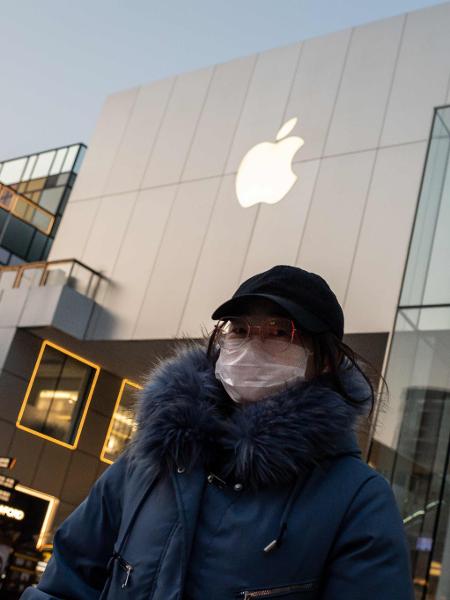 Mulher usa máscara de proteção em frente a uma loja da Apple em Beijing, na China - Nicolas Asfouri/AFP