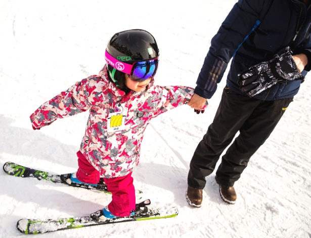 A pequena Shun Yu, 4, segura as mãos do pai em uma pista de iniciantes no resort Blue Mountain, em Ontário, no Canadá - Tara Walton/The New York Times