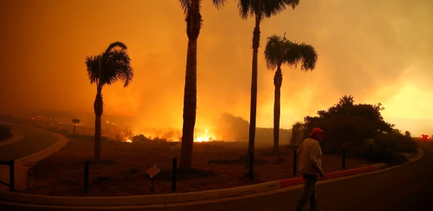 Homem caminha em bairro tomado pelas chamas na Califórnia - ERIC THAYER/REUTERS