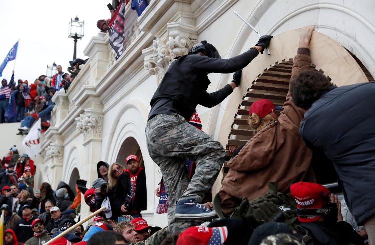 06.jan.21 - Manifestantes pró-Trump escalam um muro durante invasão ao Capitólio dos EUA