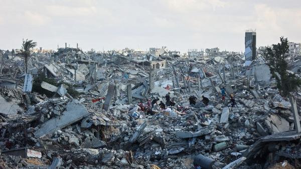 Palestinos vasculham escombros de prédios em meio à destruição generalizada causada pelos bombardeios israelenses em Khan Yunis, no sul da Faixa de Gaza