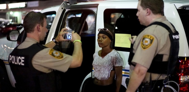 Policial tira uma foto de uma mulher detida durante protesto em Ferguson - Rick Wilking/Reuters